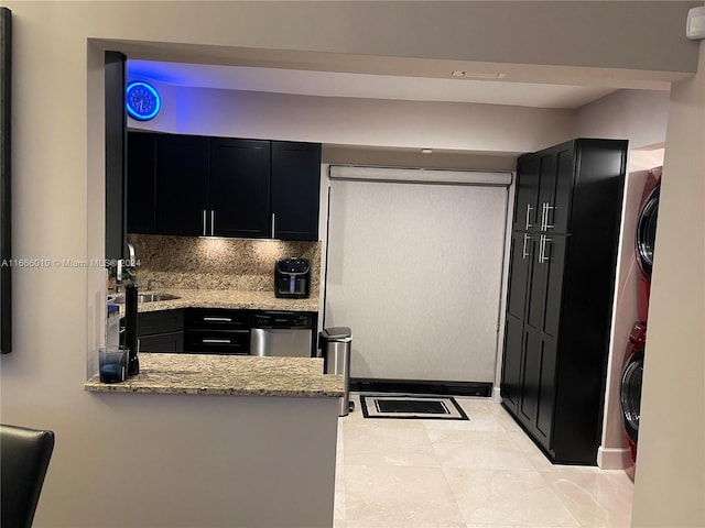 kitchen featuring light stone counters, light tile patterned flooring, tasteful backsplash, sink, and kitchen peninsula