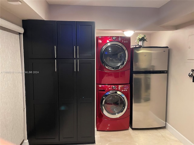 laundry room featuring stacked washer and clothes dryer, cabinets, and light tile patterned flooring