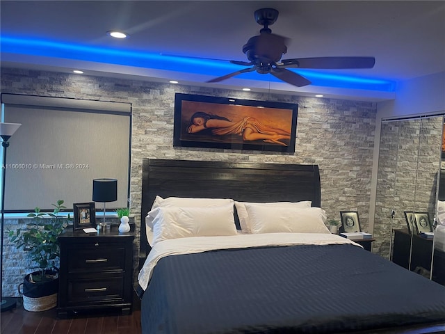 bedroom featuring ceiling fan, a fireplace, and dark wood-type flooring