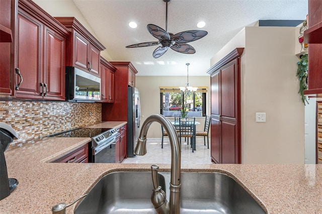 7037 Marlberry Ln, Tamarac, FL 33321 - kitchen with a sink, stainless steel appliances, ceiling fan with notable chandelier, backsplash, and reddish brown cabinets
