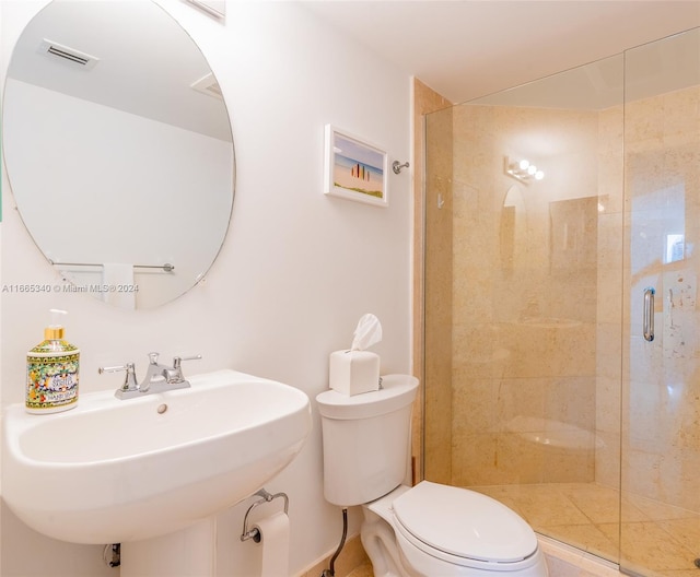 bathroom featuring toilet, sink, and a shower with shower door