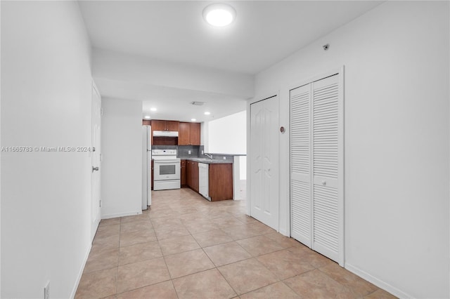 kitchen with tasteful backsplash, sink, light tile patterned floors, and white appliances