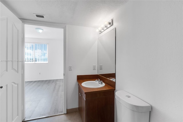 bathroom featuring vanity, toilet, a textured ceiling, and hardwood / wood-style floors