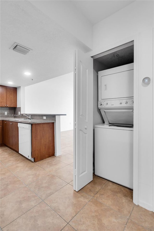 laundry room featuring light tile patterned flooring and stacked washer and clothes dryer