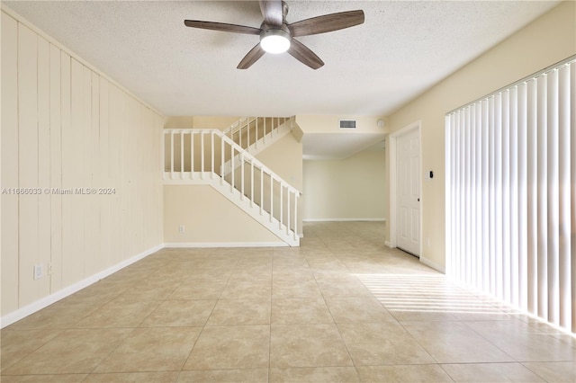 spare room with ceiling fan, light tile patterned flooring, and a textured ceiling