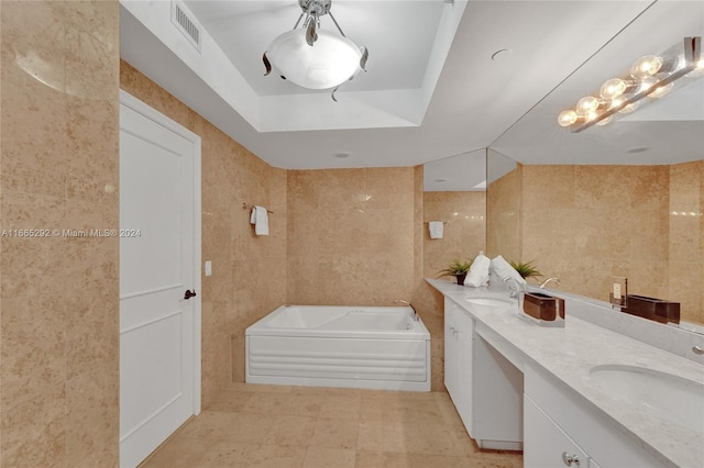 bathroom with vanity, a raised ceiling, a washtub, tile walls, and tile patterned flooring