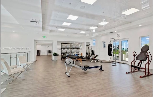 workout area with light hardwood / wood-style flooring and a paneled ceiling