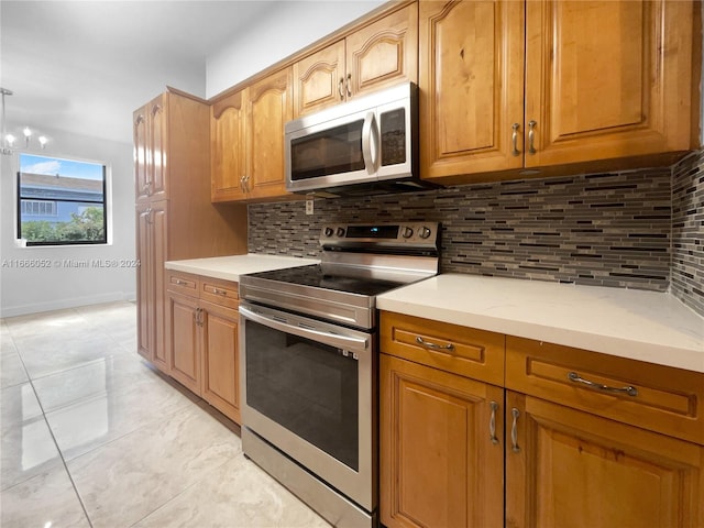 kitchen with light stone countertops, light tile patterned floors, appliances with stainless steel finishes, and tasteful backsplash