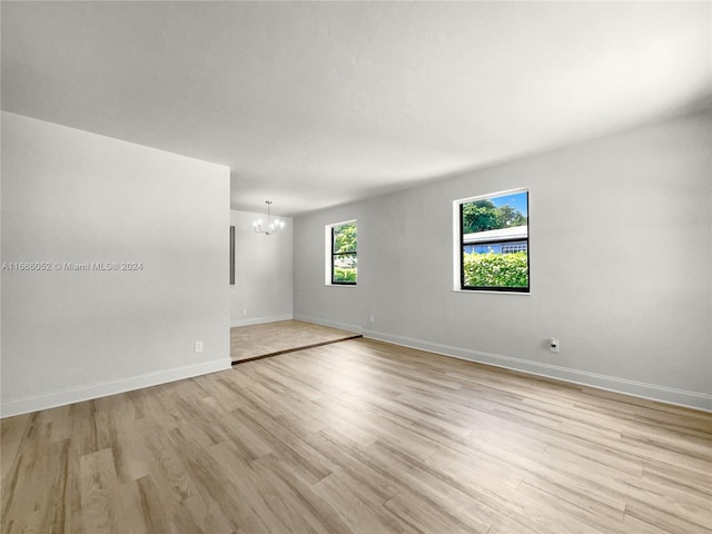 empty room with an inviting chandelier and light hardwood / wood-style flooring