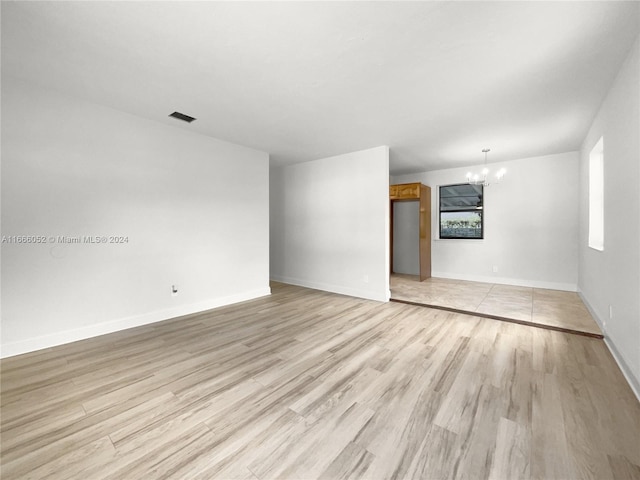 empty room featuring a chandelier and light hardwood / wood-style flooring