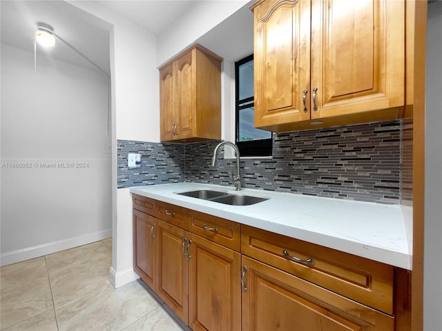 kitchen featuring decorative backsplash, sink, light tile patterned flooring, and light stone counters