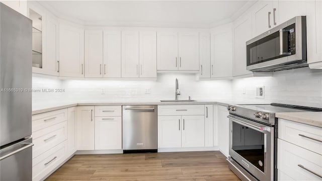 kitchen with white cabinets, appliances with stainless steel finishes, light wood-type flooring, and sink