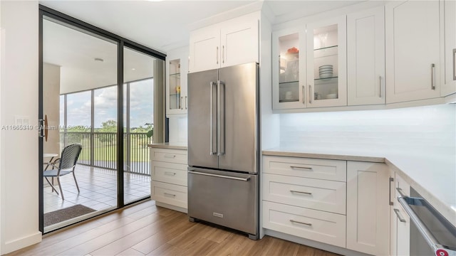 kitchen with light hardwood / wood-style flooring, stainless steel appliances, white cabinetry, and a wall of windows