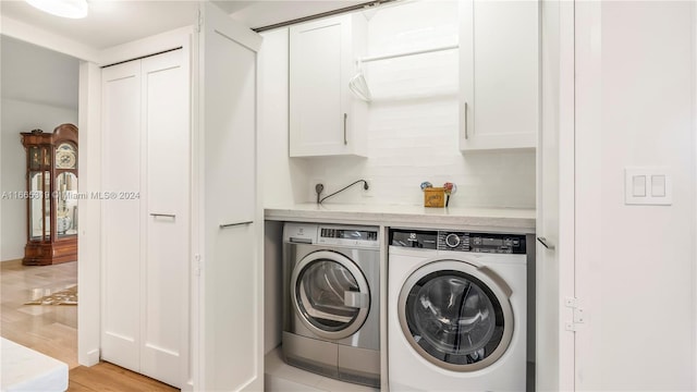 laundry room with washer and clothes dryer, cabinets, and light hardwood / wood-style flooring