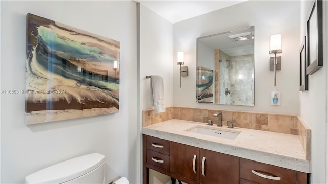 bathroom with a tile shower, vanity, and toilet