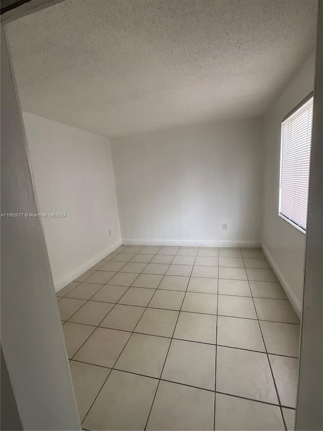 unfurnished room featuring a textured ceiling and light tile patterned floors