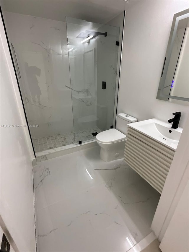 bathroom with vanity, toilet, and tiled shower