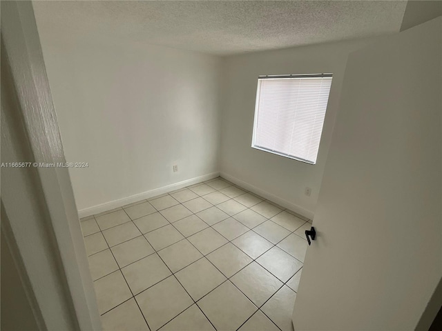 spare room with a textured ceiling and light tile patterned floors