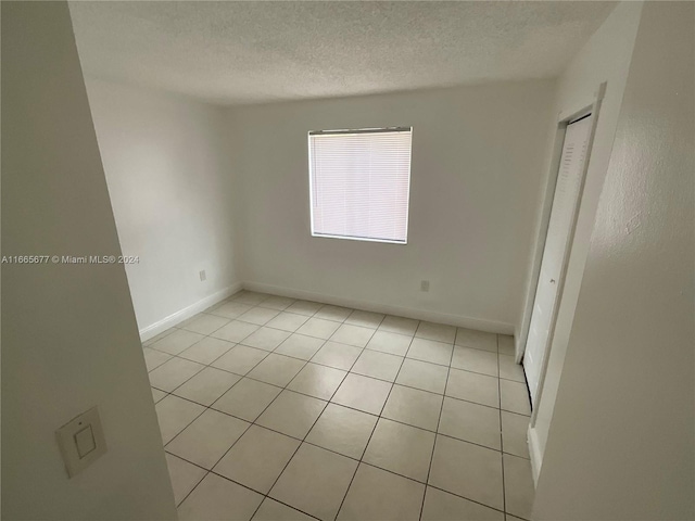 unfurnished room with a textured ceiling and light tile patterned floors