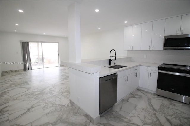 kitchen featuring white cabinets, sink, kitchen peninsula, backsplash, and stainless steel appliances