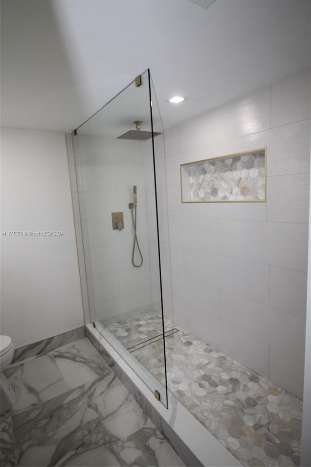 bathroom with a tile shower and toilet