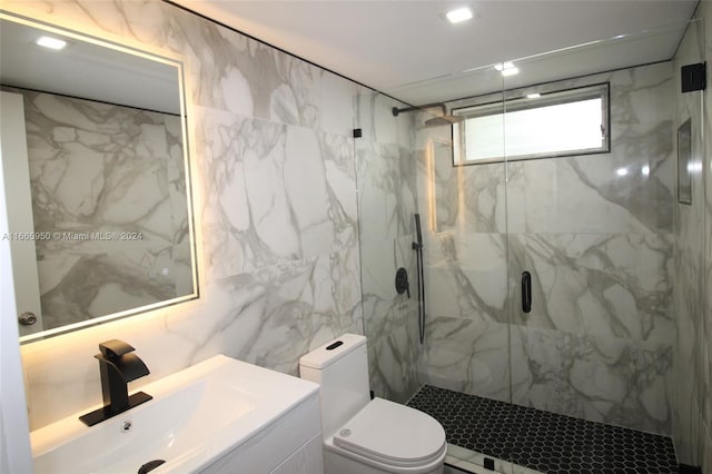 bathroom with tile walls, a shower with door, vanity, and toilet