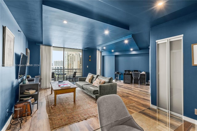 living area with baseboards, wood finished floors, and recessed lighting