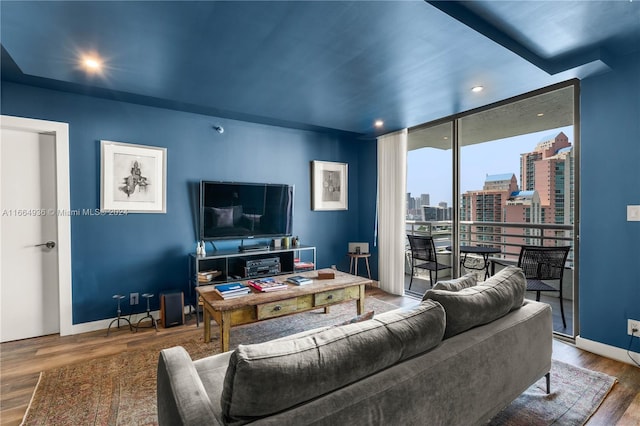 living room featuring baseboards, recessed lighting, wood finished floors, and a wall of windows