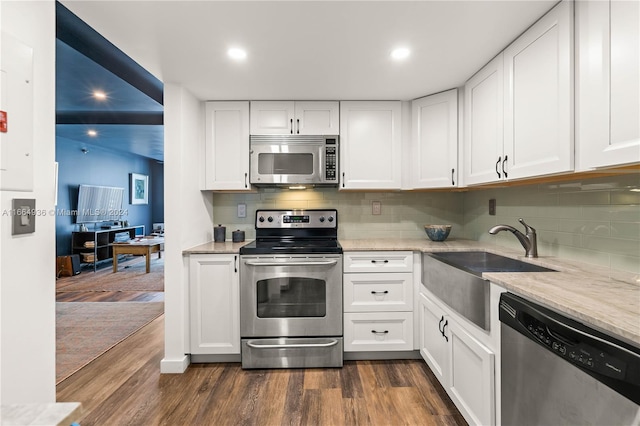 kitchen with backsplash, stainless steel appliances, dark hardwood / wood-style floors, and white cabinetry