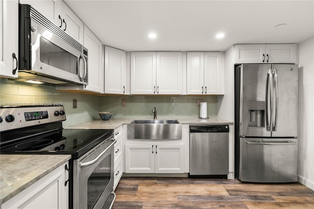 kitchen featuring white cabinetry, tasteful backsplash, stainless steel appliances, wood-type flooring, and sink