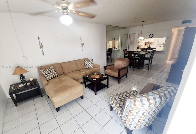 living room featuring light tile patterned floors, a textured ceiling, and ceiling fan