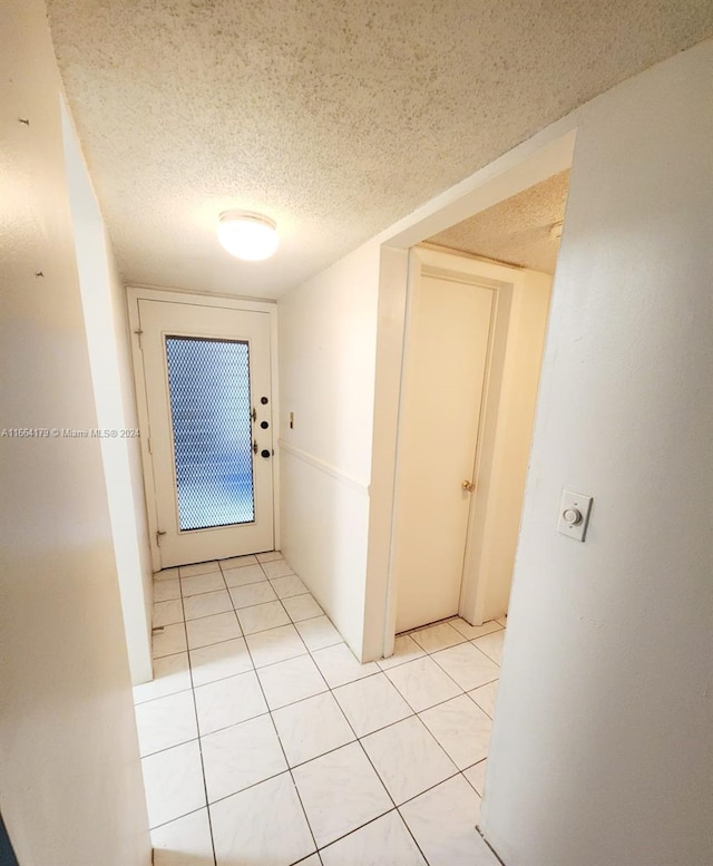 hall with light tile patterned floors and a textured ceiling