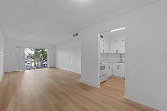 unfurnished living room featuring a textured ceiling, light hardwood / wood-style flooring, and sink