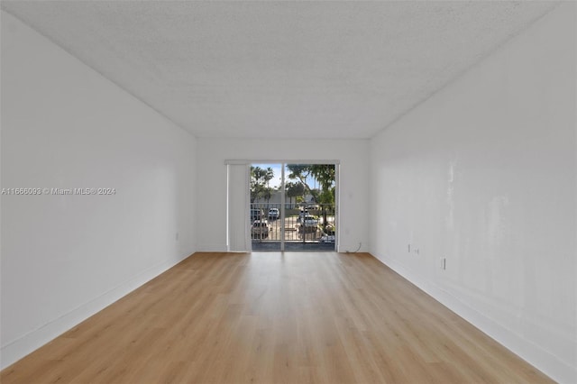 spare room featuring a textured ceiling and light hardwood / wood-style flooring