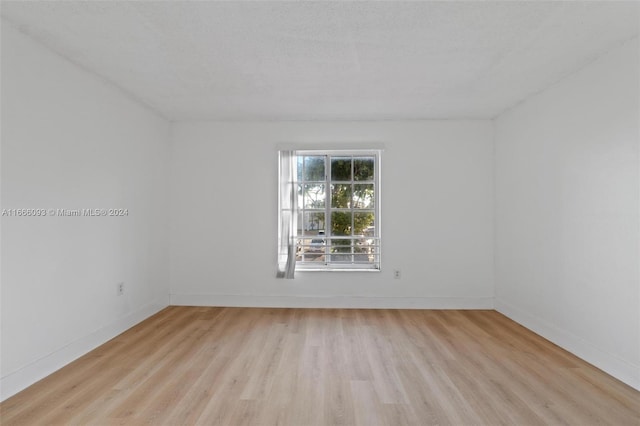 spare room with light hardwood / wood-style floors and a textured ceiling