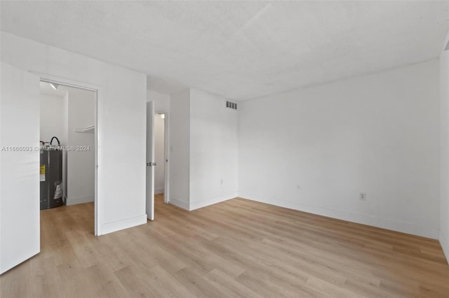 spare room with light wood-type flooring and a textured ceiling