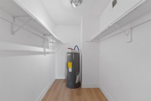 walk in closet with electric water heater and hardwood / wood-style flooring