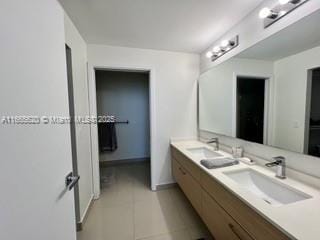 full bathroom with baseboards, tile patterned floors, double vanity, and a sink