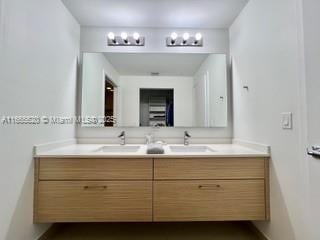 bathroom with a sink, double vanity, and baseboards
