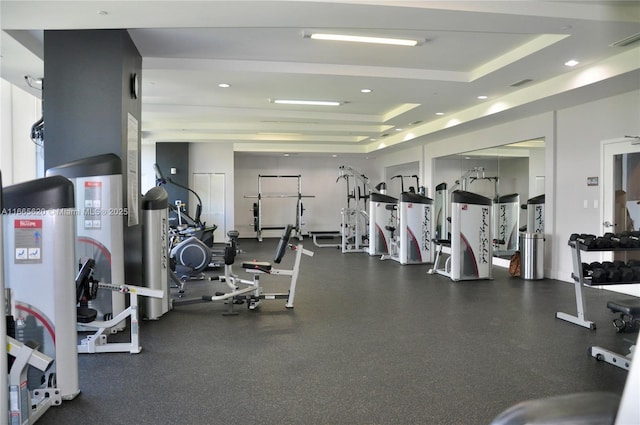 gym with a tray ceiling, visible vents, and recessed lighting