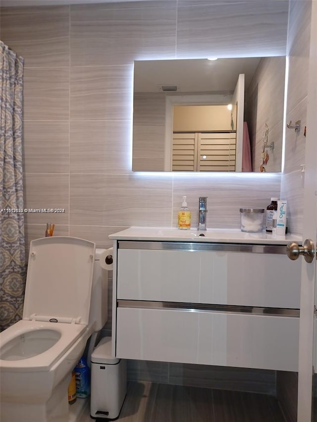 bathroom featuring decorative backsplash, tile walls, vanity, and toilet