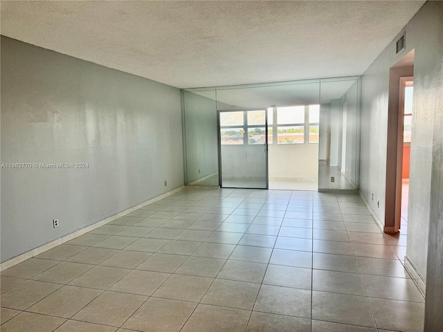 unfurnished room featuring a textured ceiling and light tile patterned floors