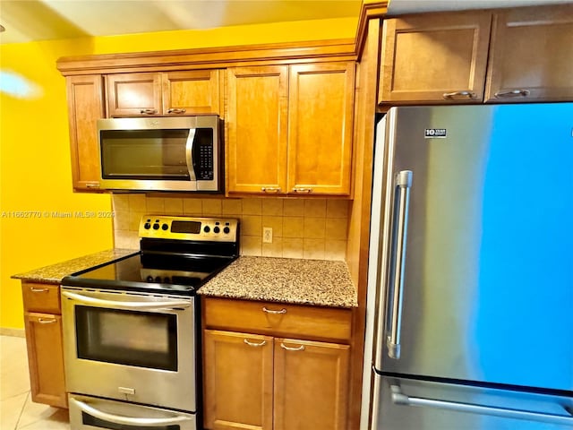 kitchen featuring decorative backsplash, appliances with stainless steel finishes, light tile patterned floors, and light stone counters