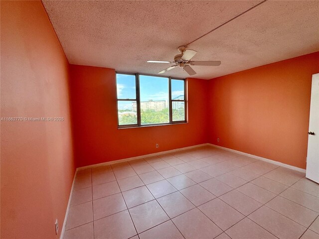 spare room featuring ceiling fan, a textured ceiling, and light tile patterned floors