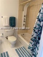 bathroom featuring toilet, shower / bathtub combination with curtain, and tile patterned floors