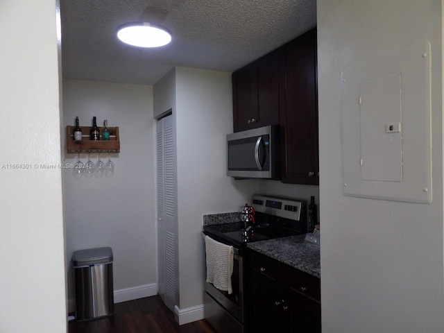 kitchen featuring electric panel, a textured ceiling, stainless steel appliances, dark stone countertops, and dark hardwood / wood-style flooring