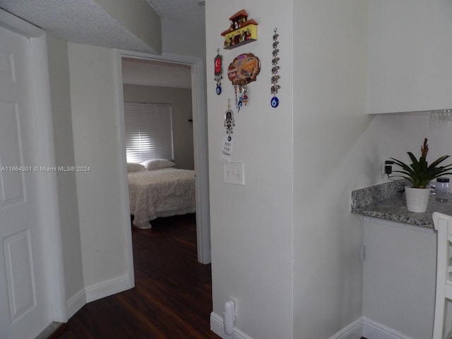 corridor with a textured ceiling and dark hardwood / wood-style floors