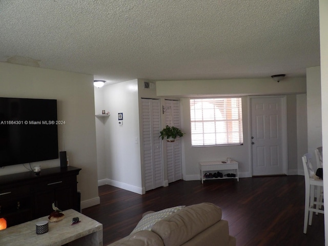 living room with a textured ceiling and dark hardwood / wood-style floors