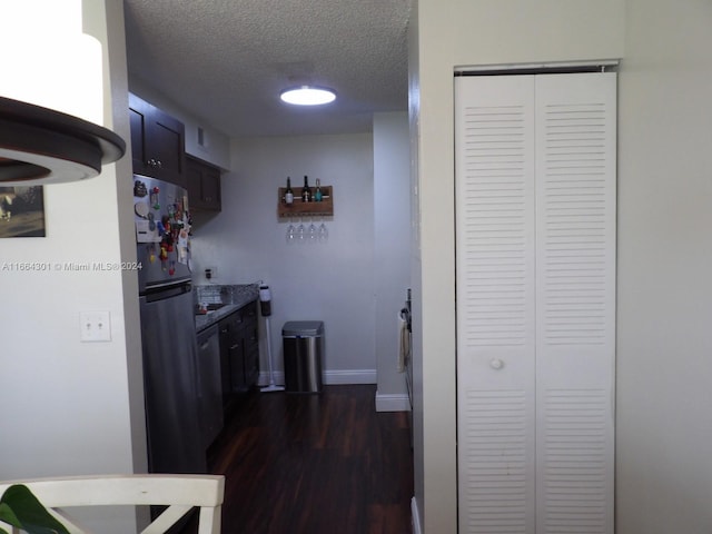 kitchen with a textured ceiling, appliances with stainless steel finishes, and dark hardwood / wood-style flooring