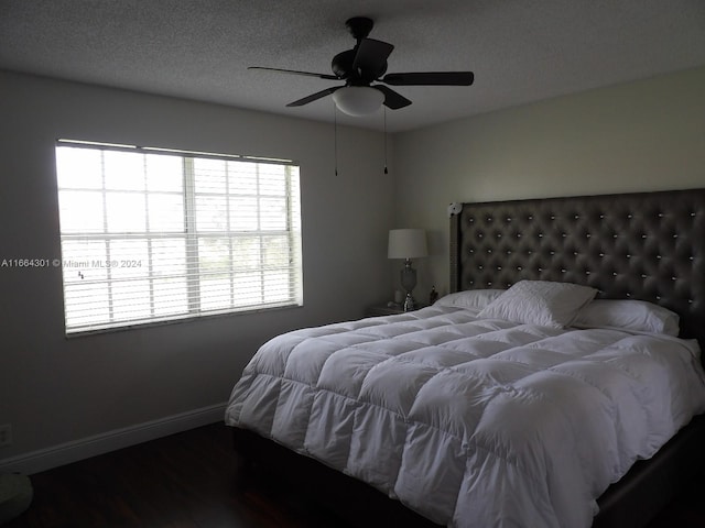 bedroom with ceiling fan, dark wood-type flooring, and a textured ceiling